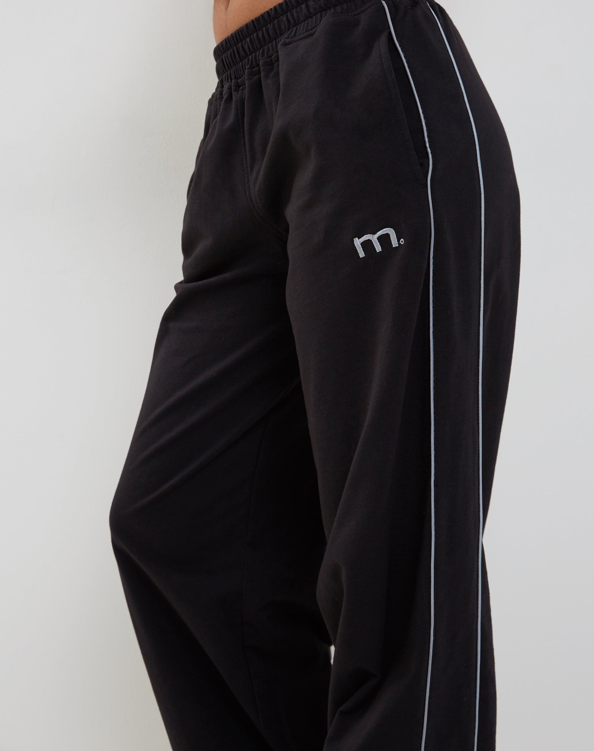 Immagine di Benton Jogger a gamba larga in nero con profili grigio scuro e ricamo "M