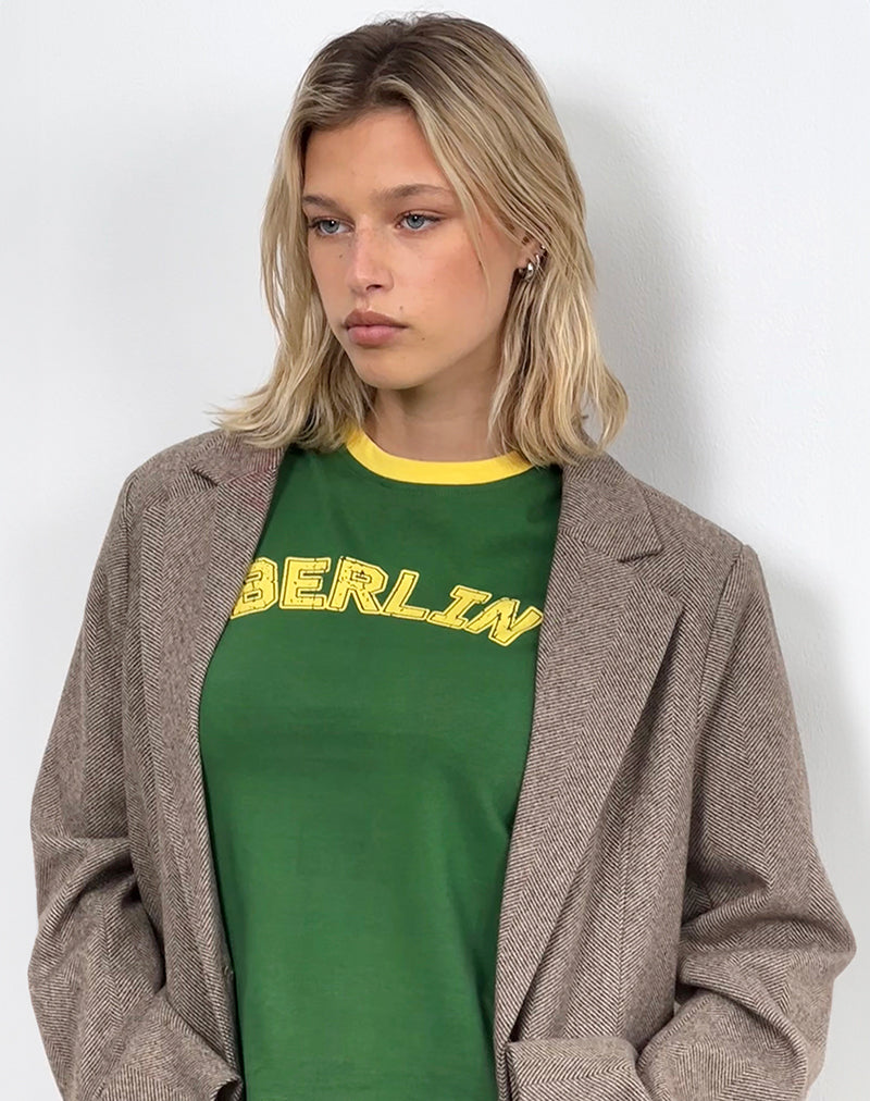 Immagine di Sakha Boxy Top in verde olmo con rilegatura gialla e stampa berlinese
