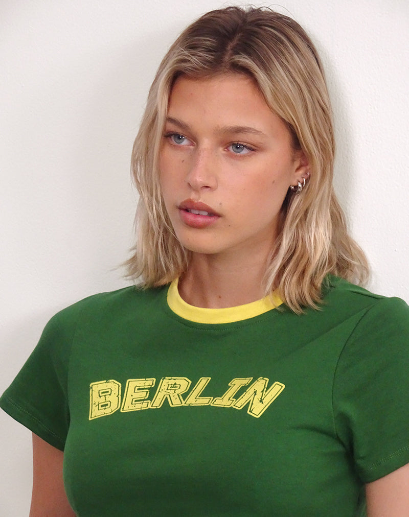 Immagine di Sakha Boxy Top in verde olmo con rilegatura gialla e stampa berlinese