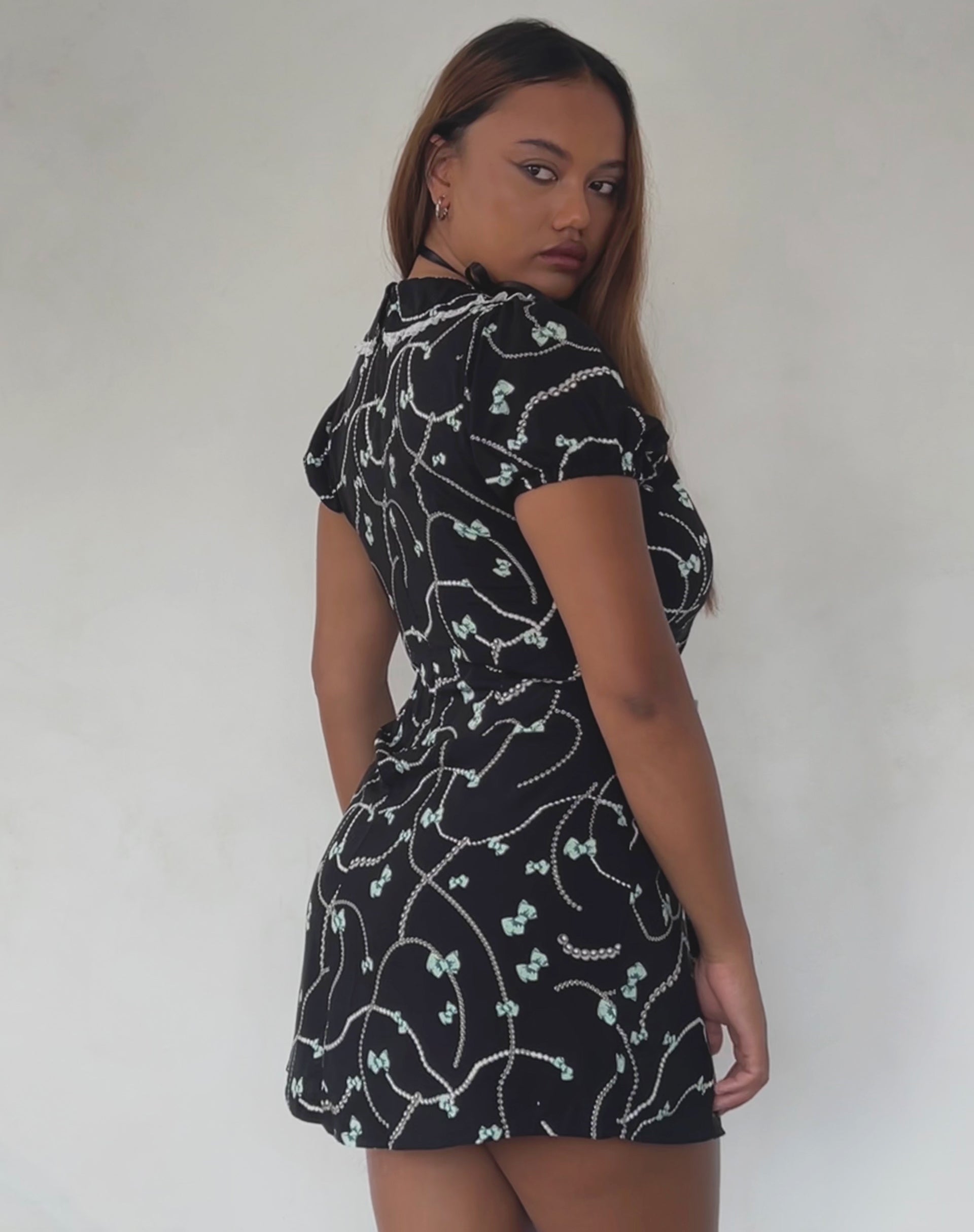 Immagine di Sulani Mini Dress in nero con stampa di perle e fiocchi